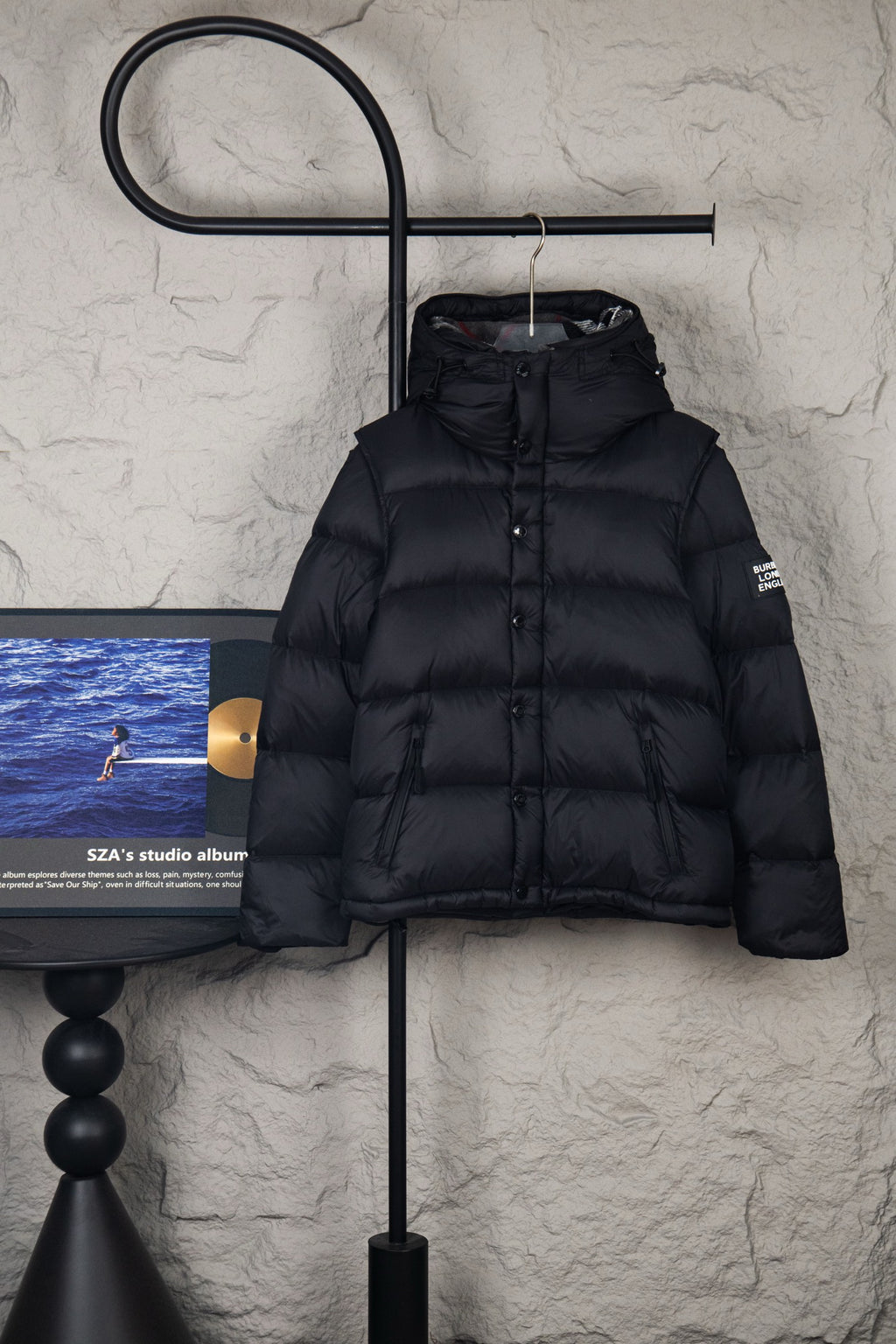 Black puffer jacket with hood and front button placket, quilted panels
