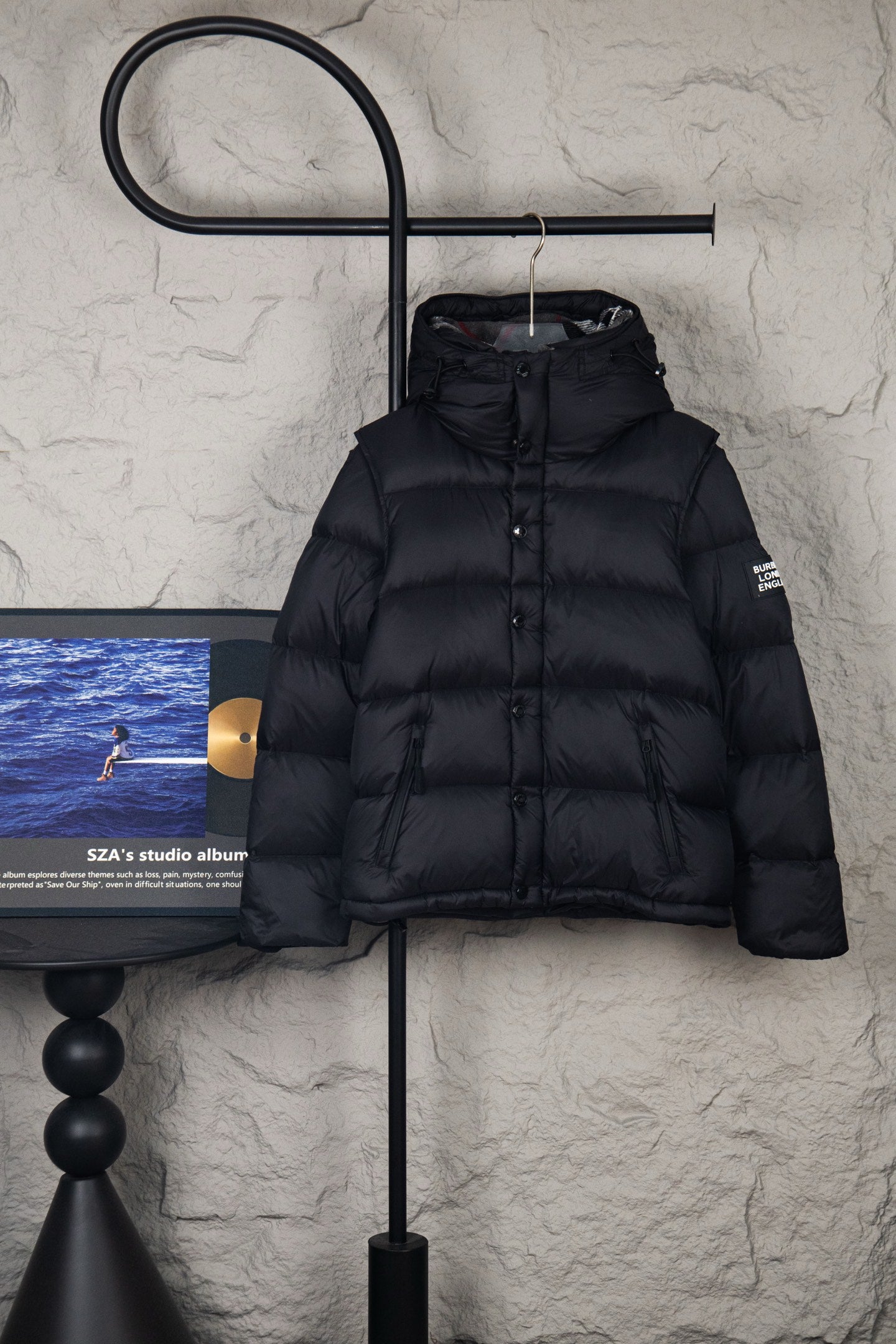 Black puffer jacket with hood and front button placket, quilted panels