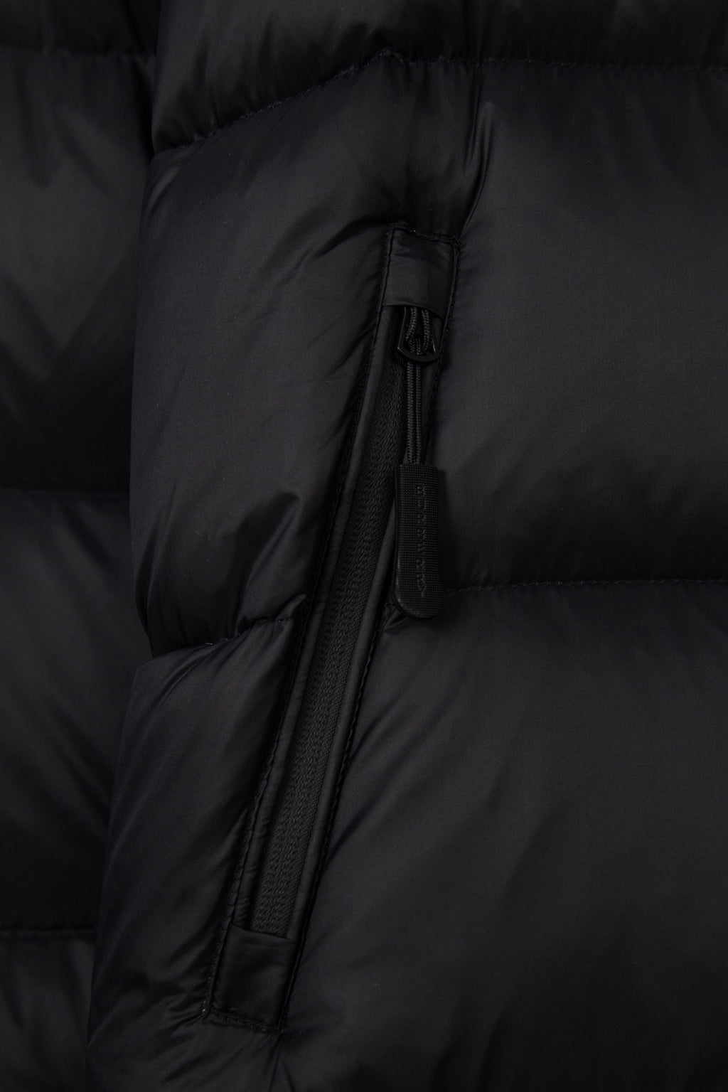 Black puffer jacket front zipper with fabric pull tab and quilted paneling