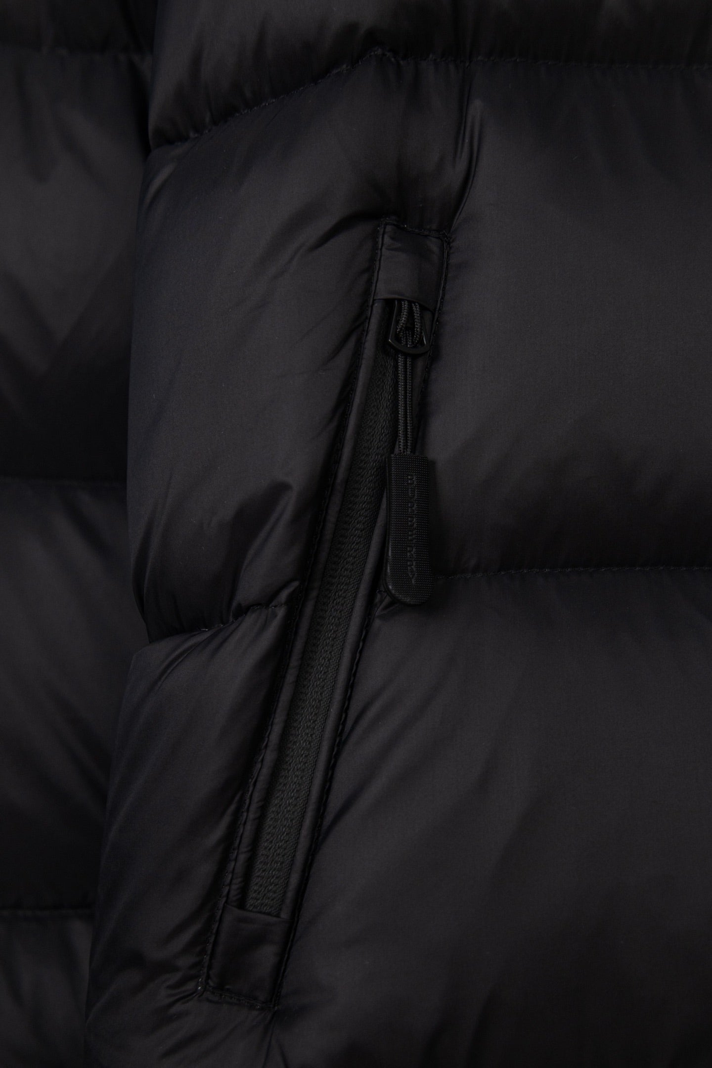 Black puffer jacket front zipper with fabric pull tab and quilted paneling