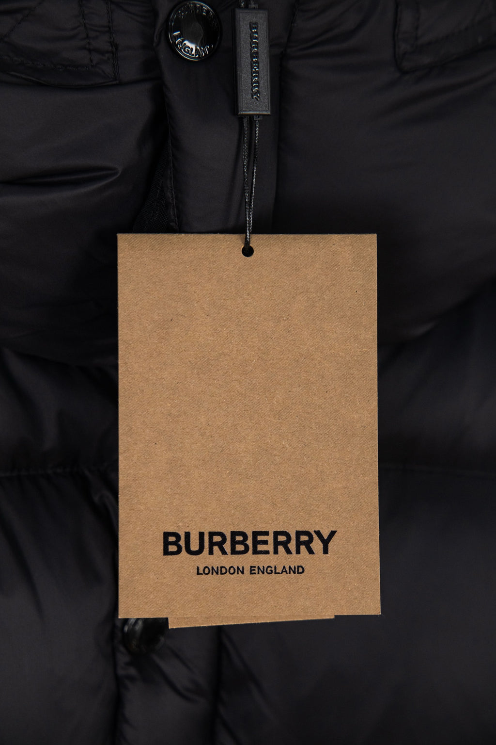 BURBERRY hang tag on black puffer jacket, reading “BURBERRY LONDON ENGLAND”