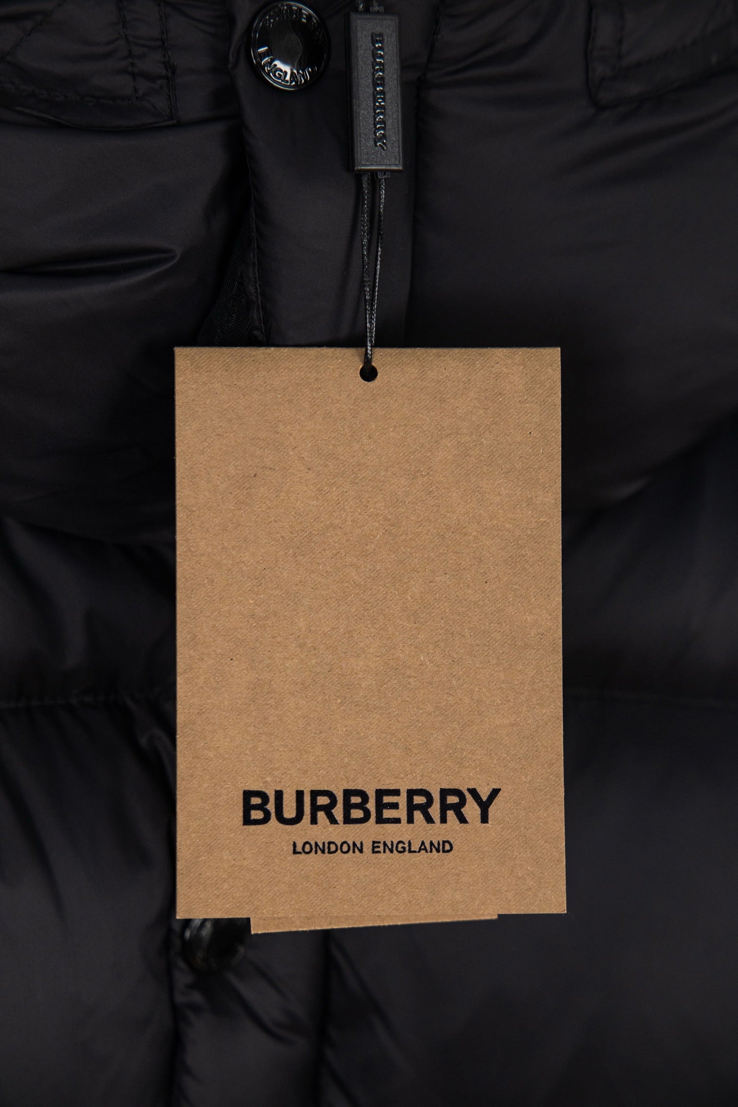 BURBERRY hang tag on black puffer jacket, reading “BURBERRY LONDON ENGLAND”