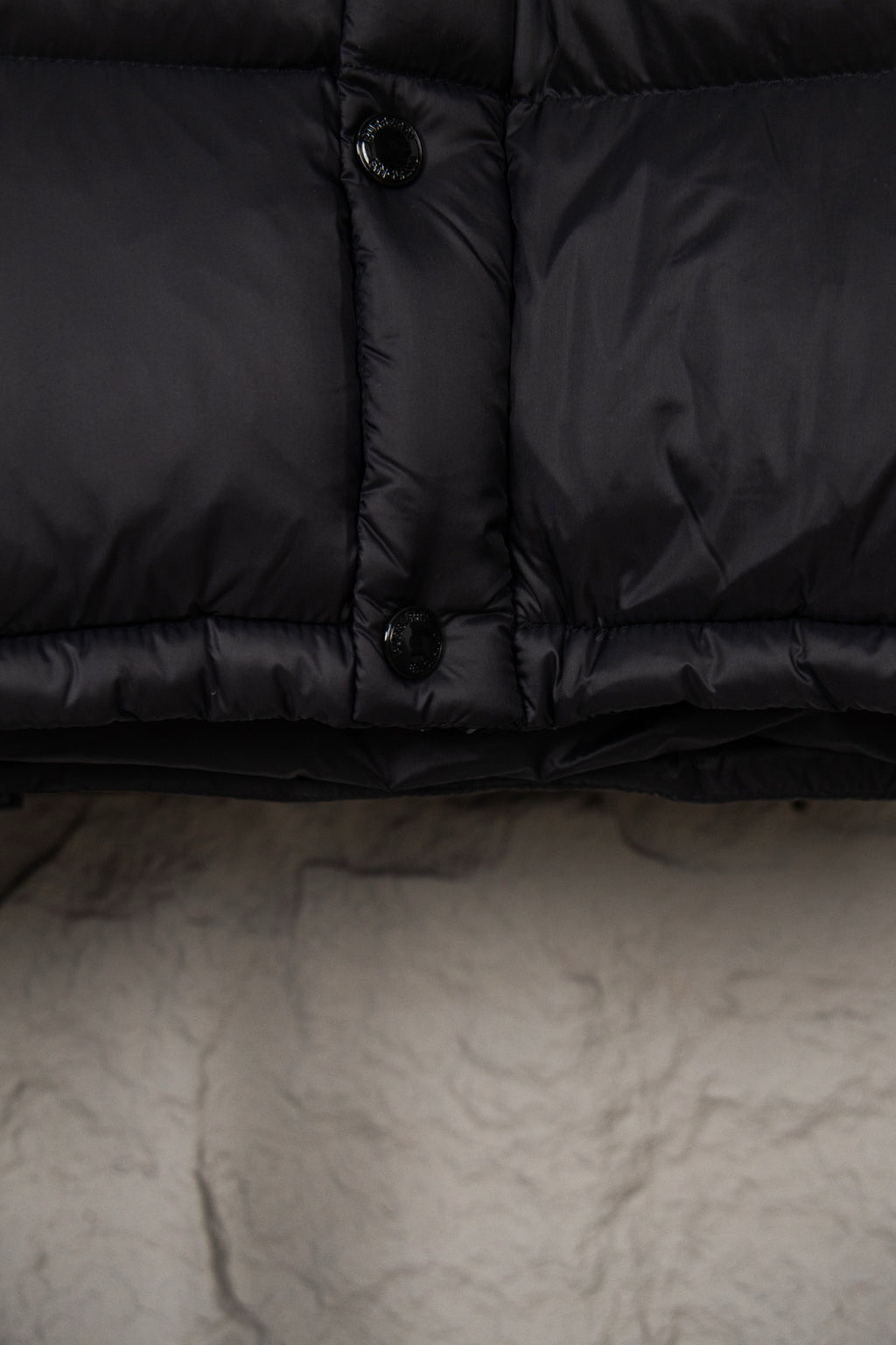 Long puffer coat hem and zipper placket with toggle button, dark fabric