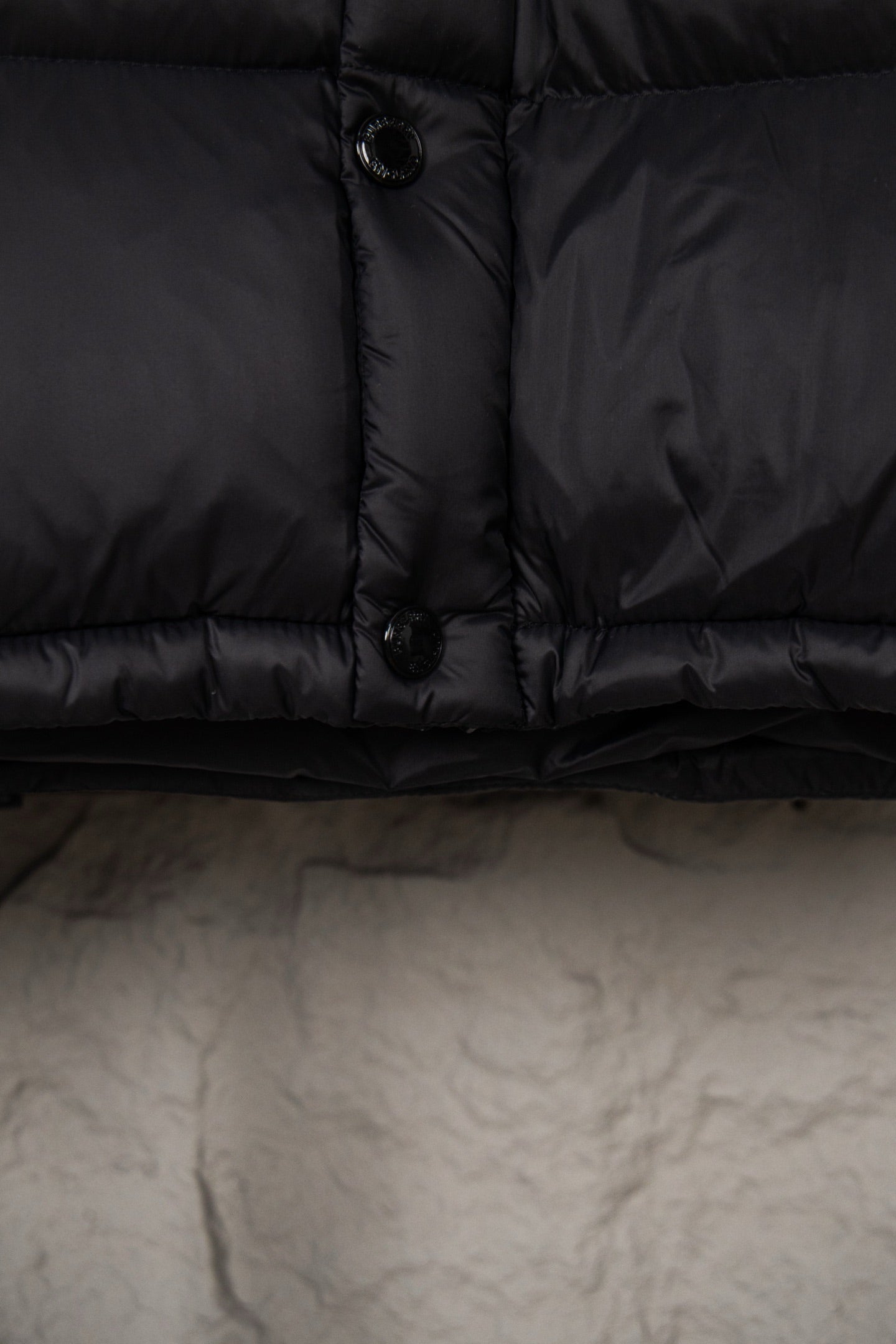 Long puffer coat hem and zipper placket with toggle button, dark fabric