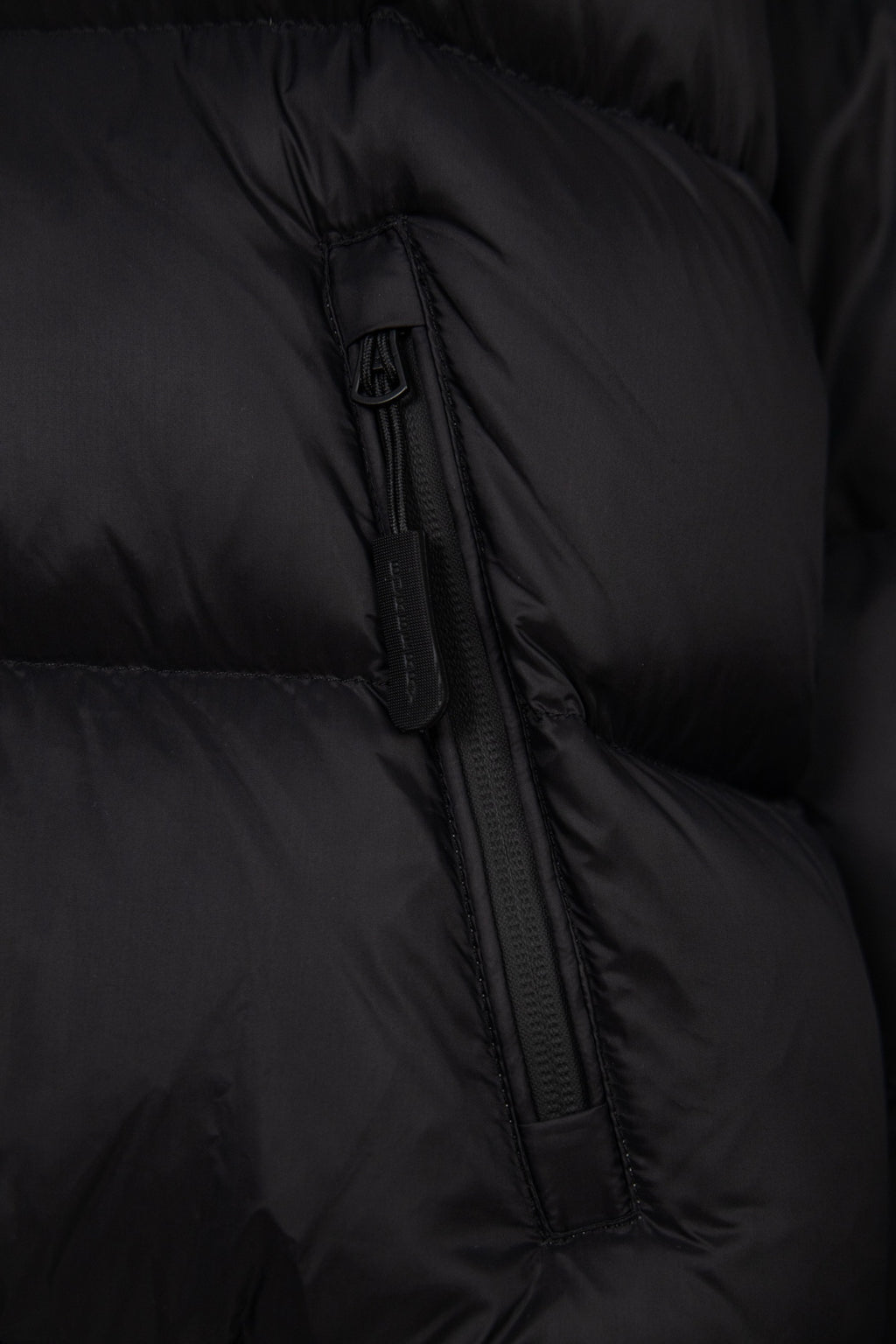 Black puffer jacket zipper detail with quilted fabric and stitched channel seams