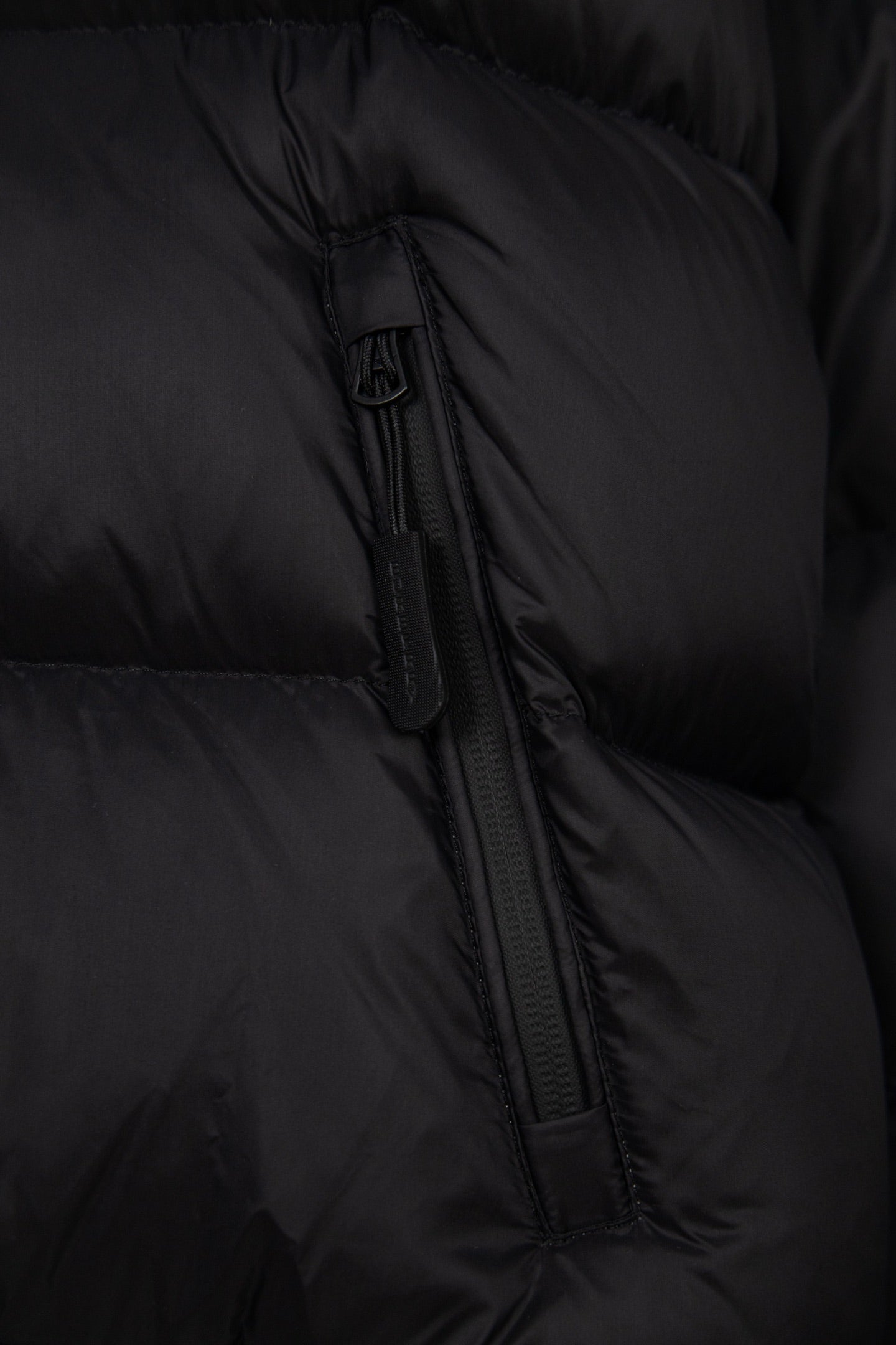 Black puffer jacket zipper detail with quilted fabric and stitched channel seams