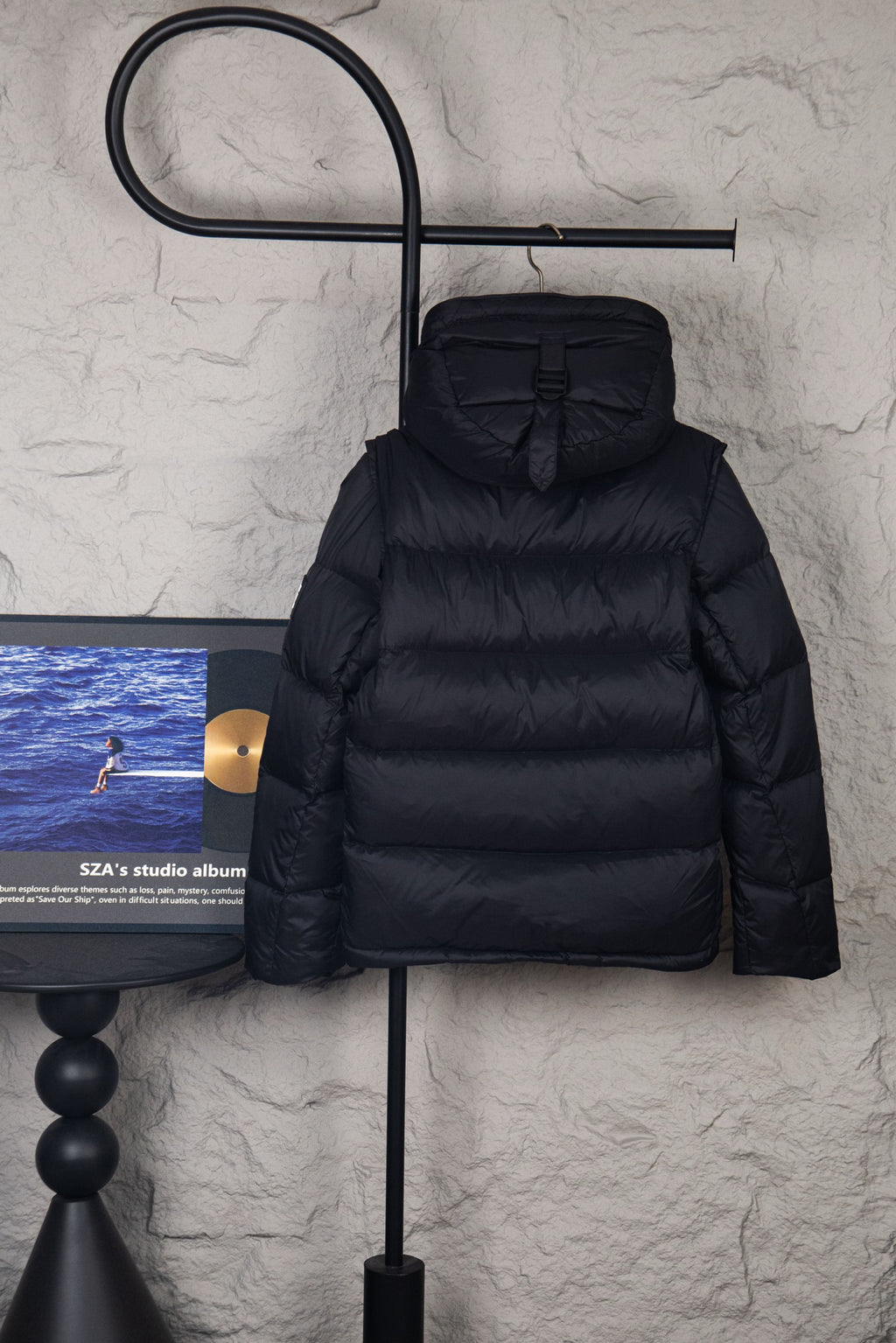 Black hooded puffer jacket with front button placket and quilted bubble stitching