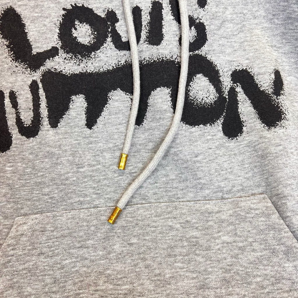 Gray Louis Vuitton hoodie close-up of black logo text and white drawstrings.