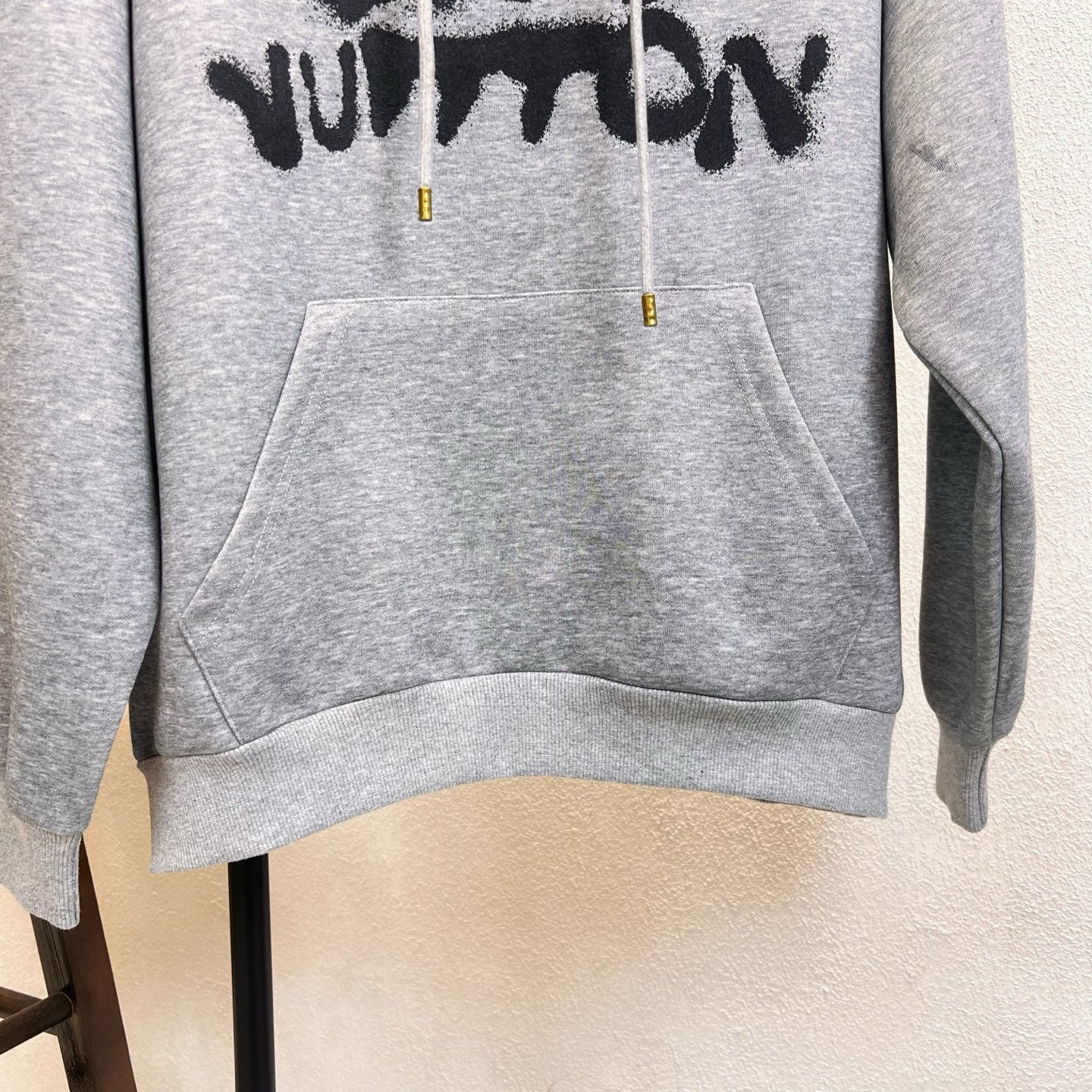 Gray Louis Vuitton hoodie front with black text graphic across chest and large pouch pocket.