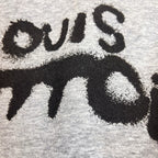 Gray Louis Vuitton hoodie fabric close-up with black stylized logo lettering.