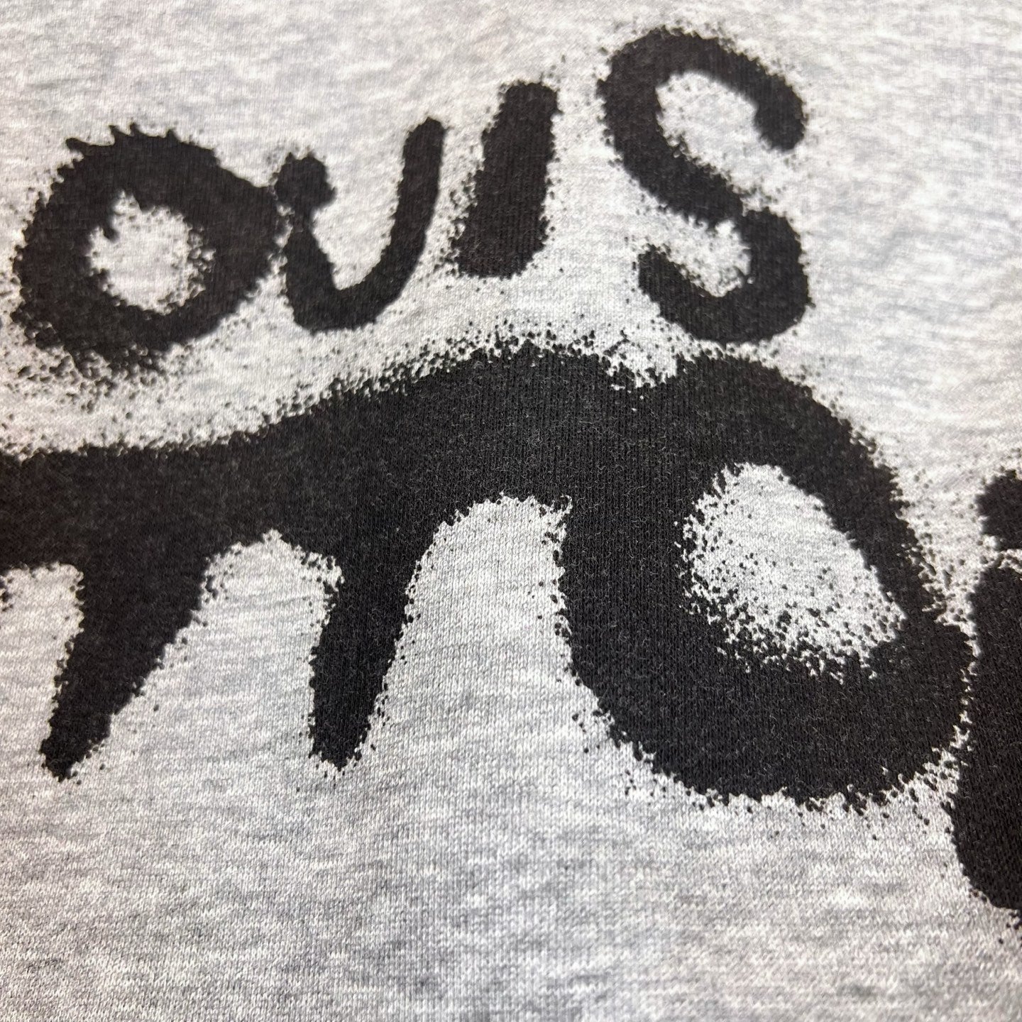 Gray Louis Vuitton hoodie fabric close-up with black stylized logo lettering.