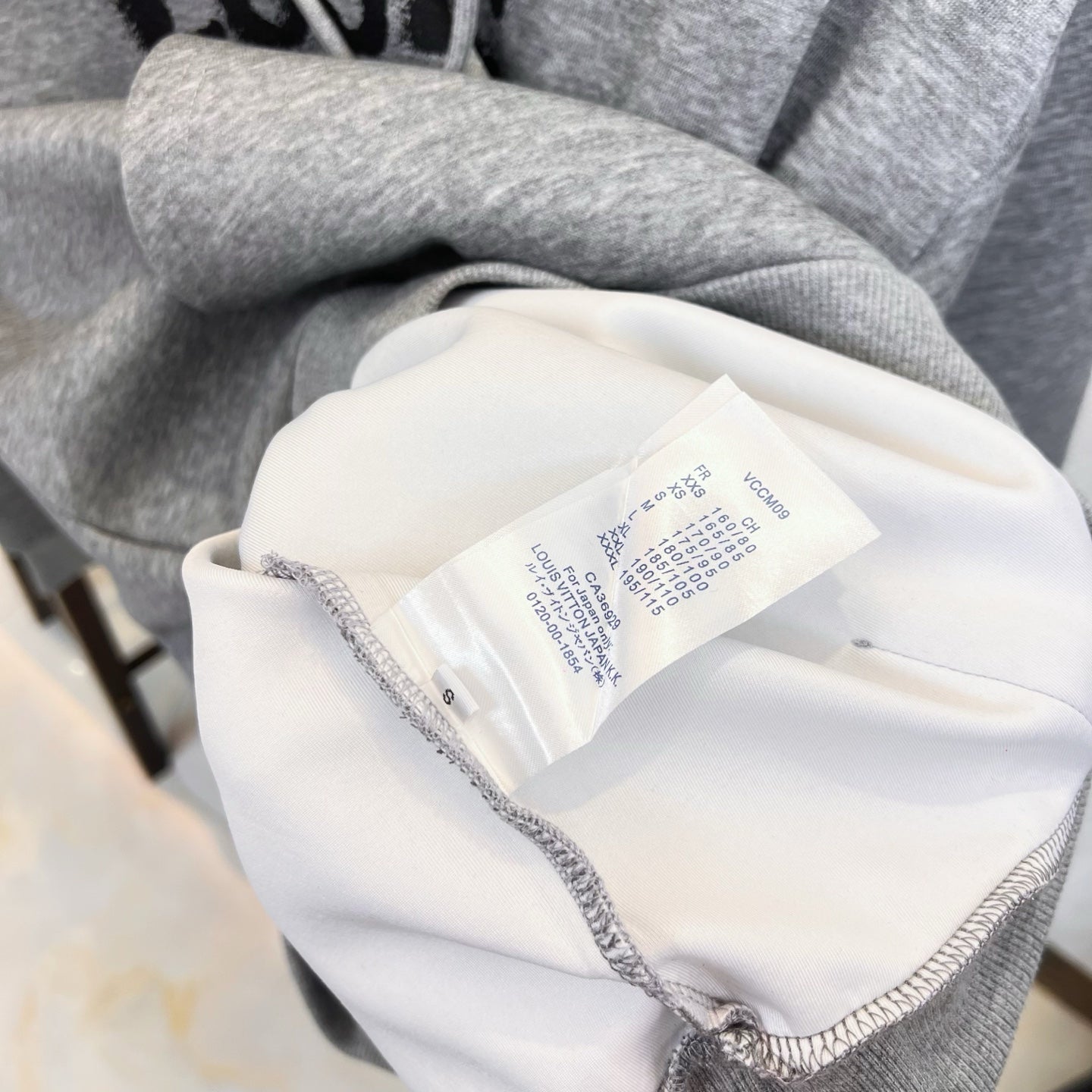 Long graphic shirt collar tag and interior label on light fabric with gray trim