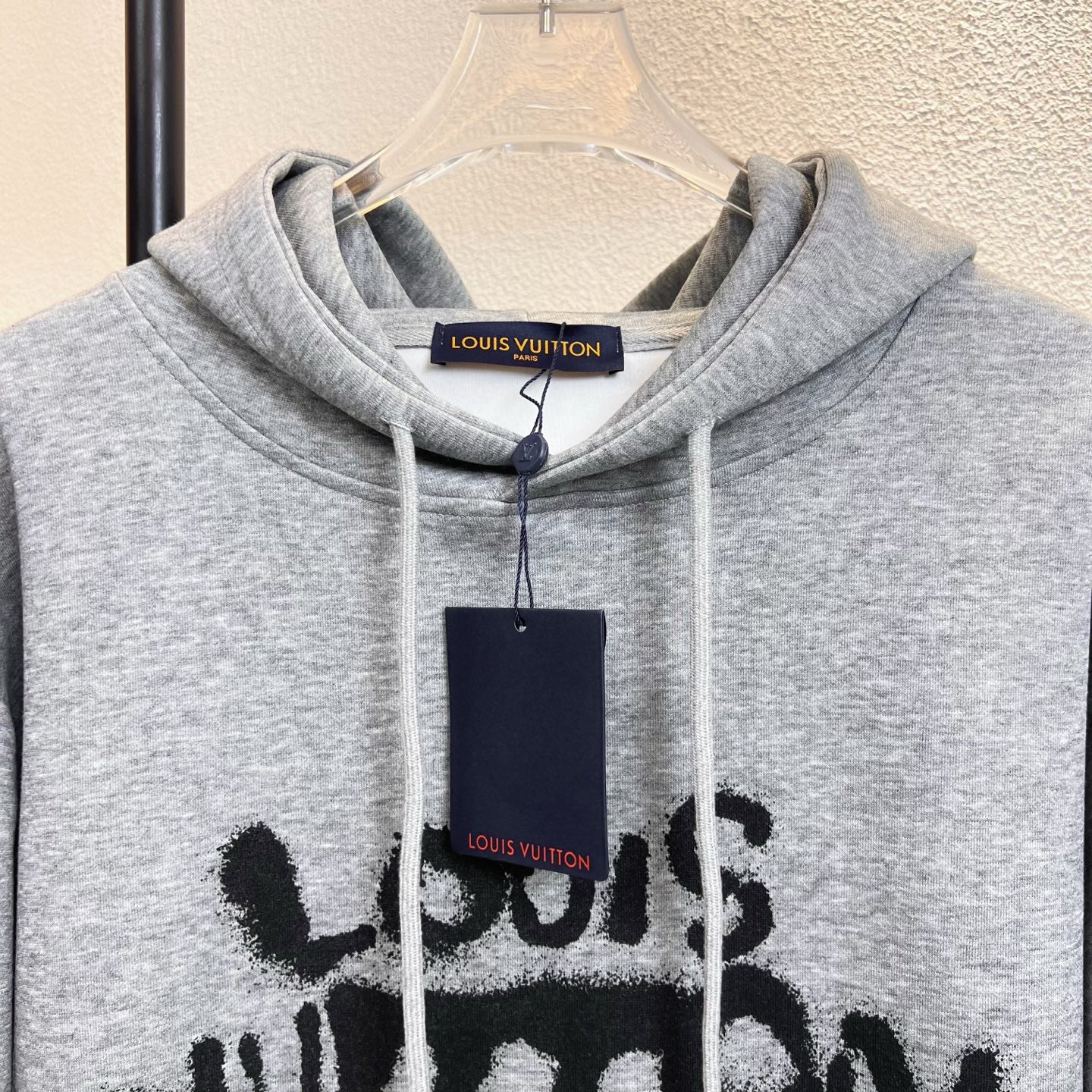 Gray Louis Vuitton hoodie close-up with drawstring hood and black graphic print.