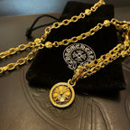 Gold-tone chain necklace with circular pendant and small cross charm on box