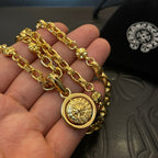 Gold chain necklace with round medallion pendant held in an open hand