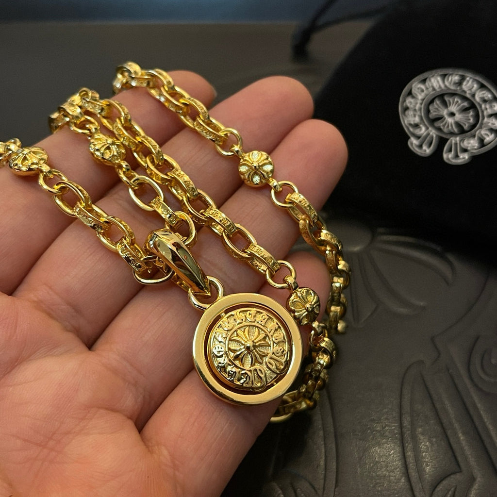 Gold-tone necklace with round medallion pendant, shown in hand close-up