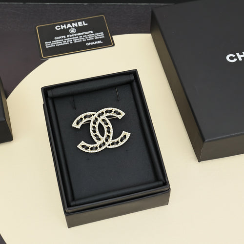 Rhinestone Chanel logo brooch on black display box, gold-tone and black enamel