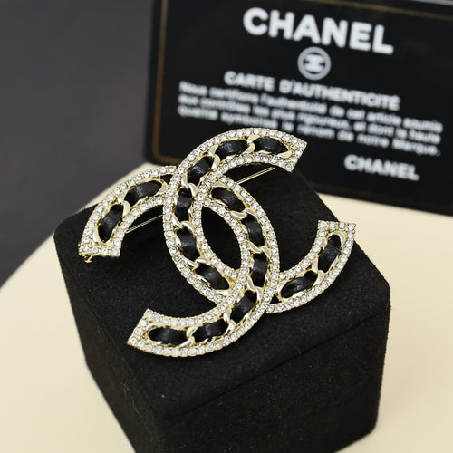 Rhinestone Chanel logo brooch with black enamel, gold-tone frame