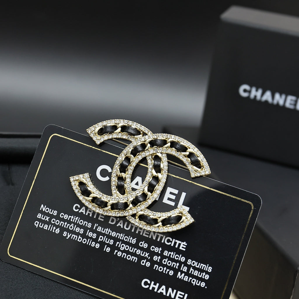 Rhinestone Chanel logo brooch with black enamel, gold-tone crystal trim