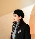 Rhinestone Chanel logo brooch on black coat lapel, worn by model