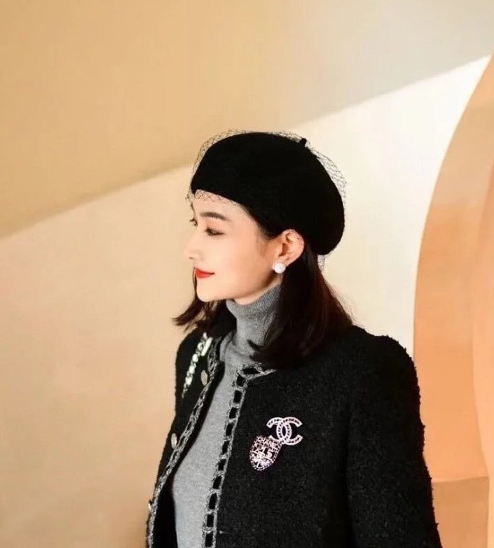 Rhinestone Chanel logo brooch on black coat lapel, worn by model