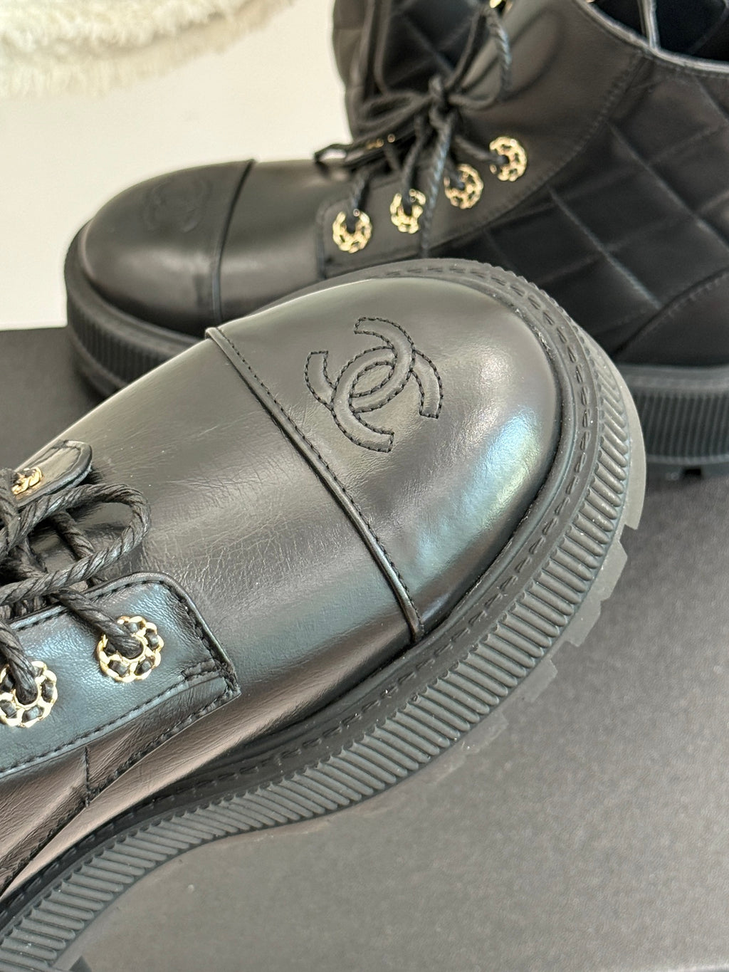 Close-up of dark leather boot with gold logo on side and ridged sole