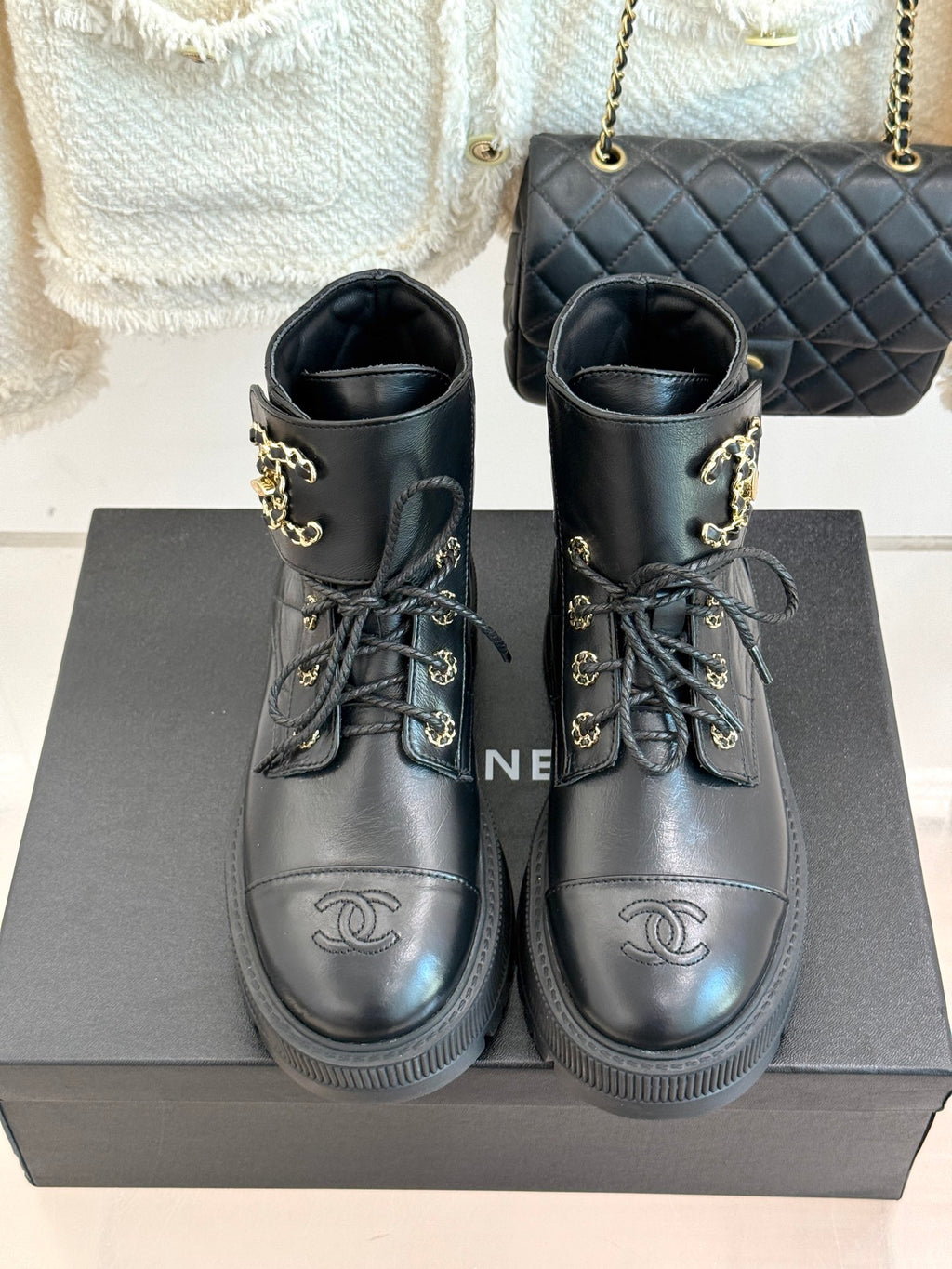 Pair of dark leather lace-up boots with gold CC-style logos and thick ribbed soles