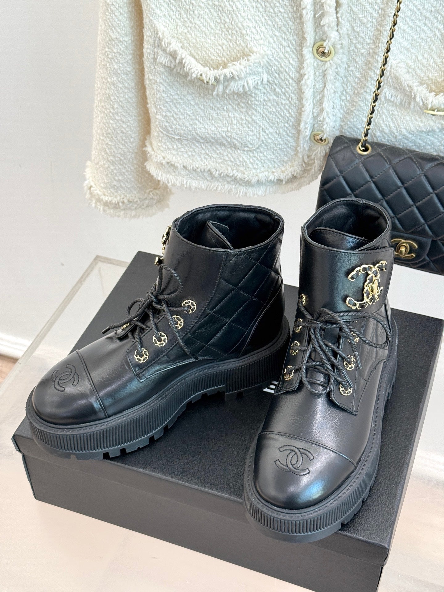 Dark high-top lace-up boots with gold logo medallion eyelets and ribbed platform sole