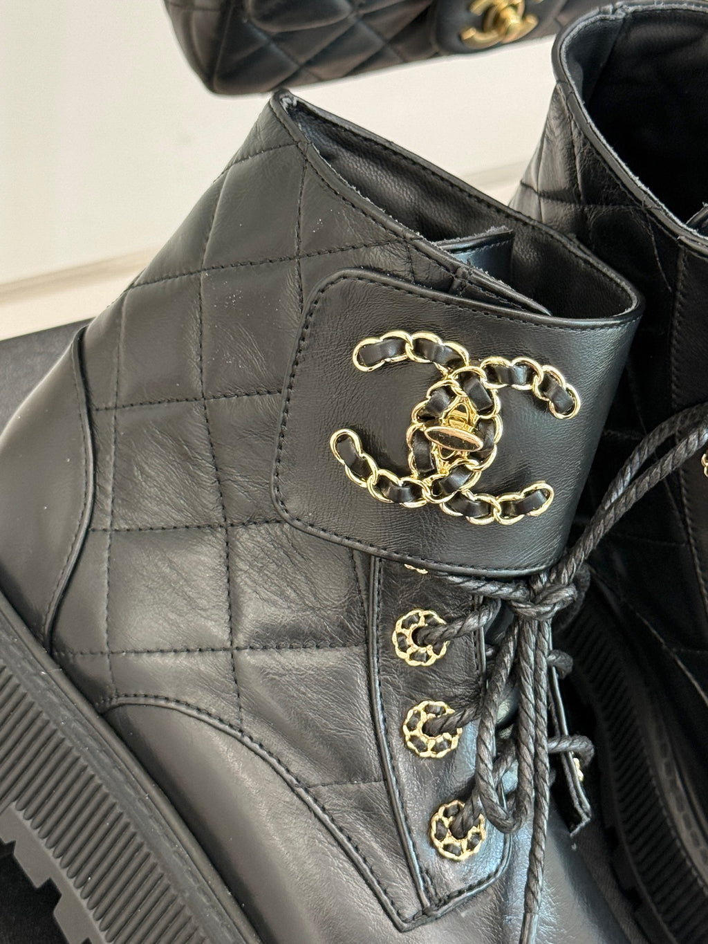 Dark quilted boot upper with gold chain lace detail and logo emblem