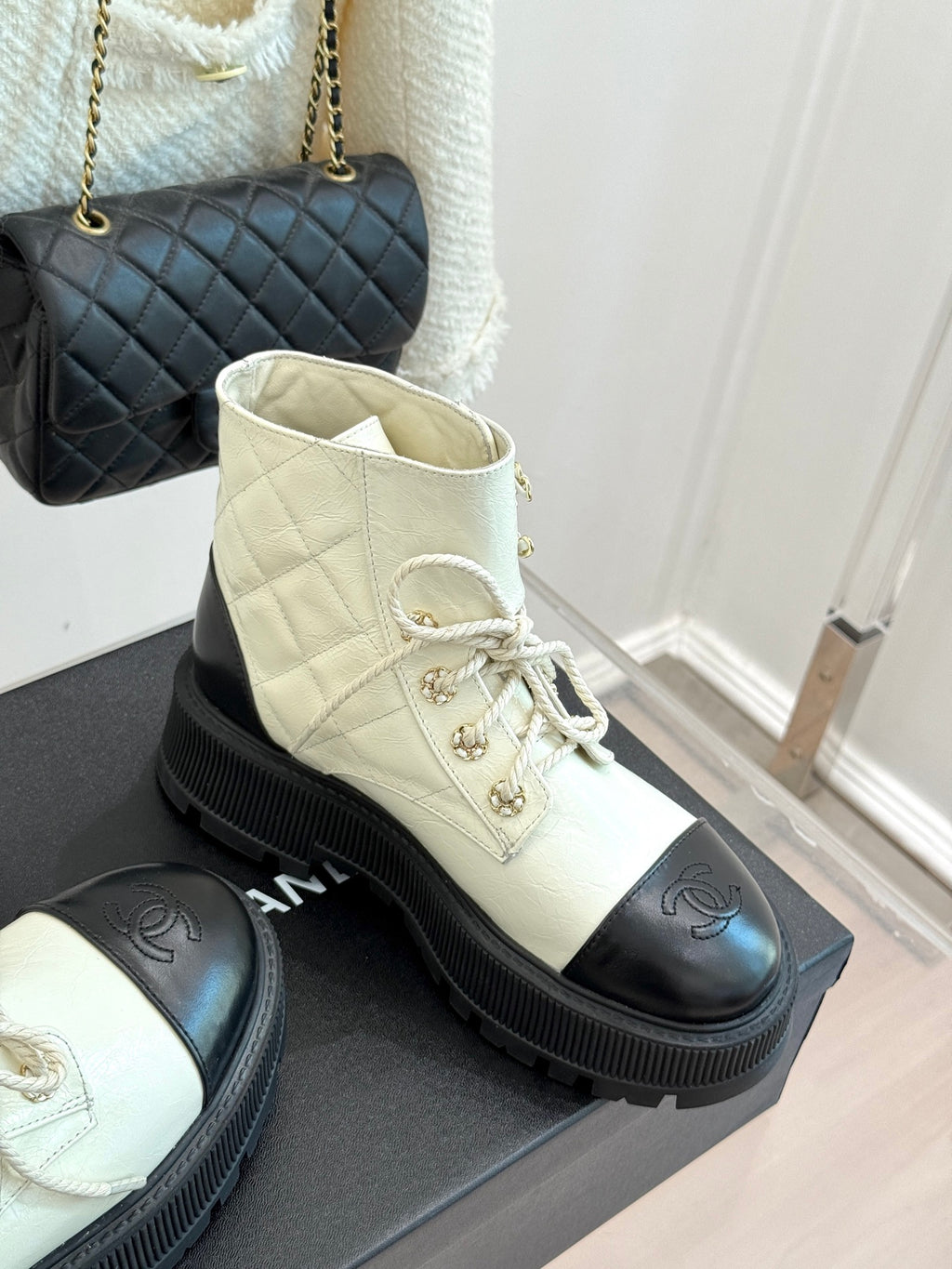 White leather lace-up ankle boot with black toe cap and ridged rubber sole