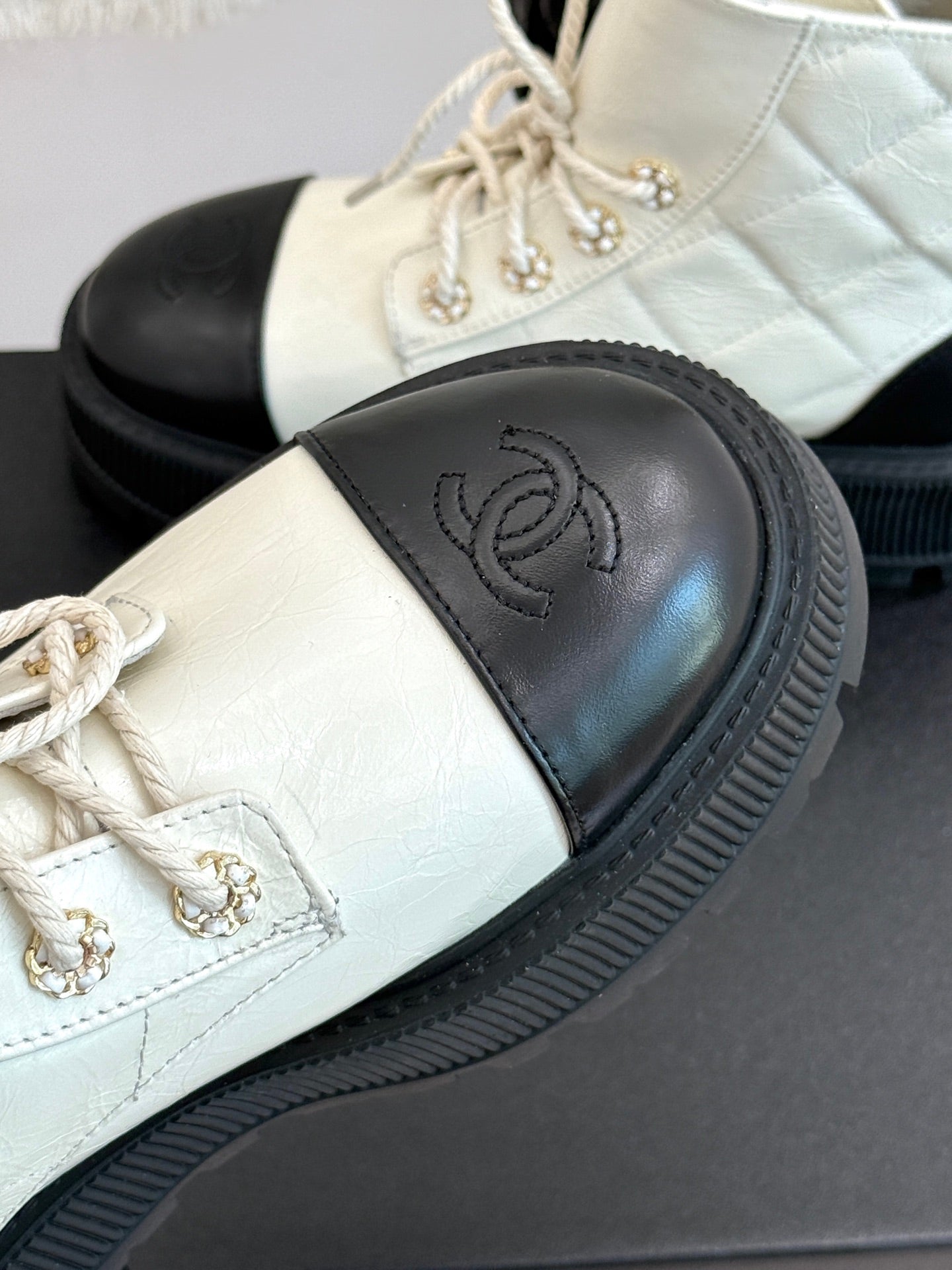 White leather ankle boot with black toe panel and ridged rubber sole