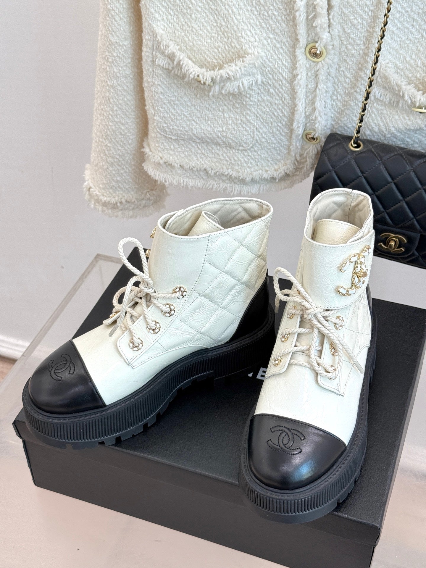 White lace-up ankle boots with black toe caps and decorative logo, thick ridged sole
