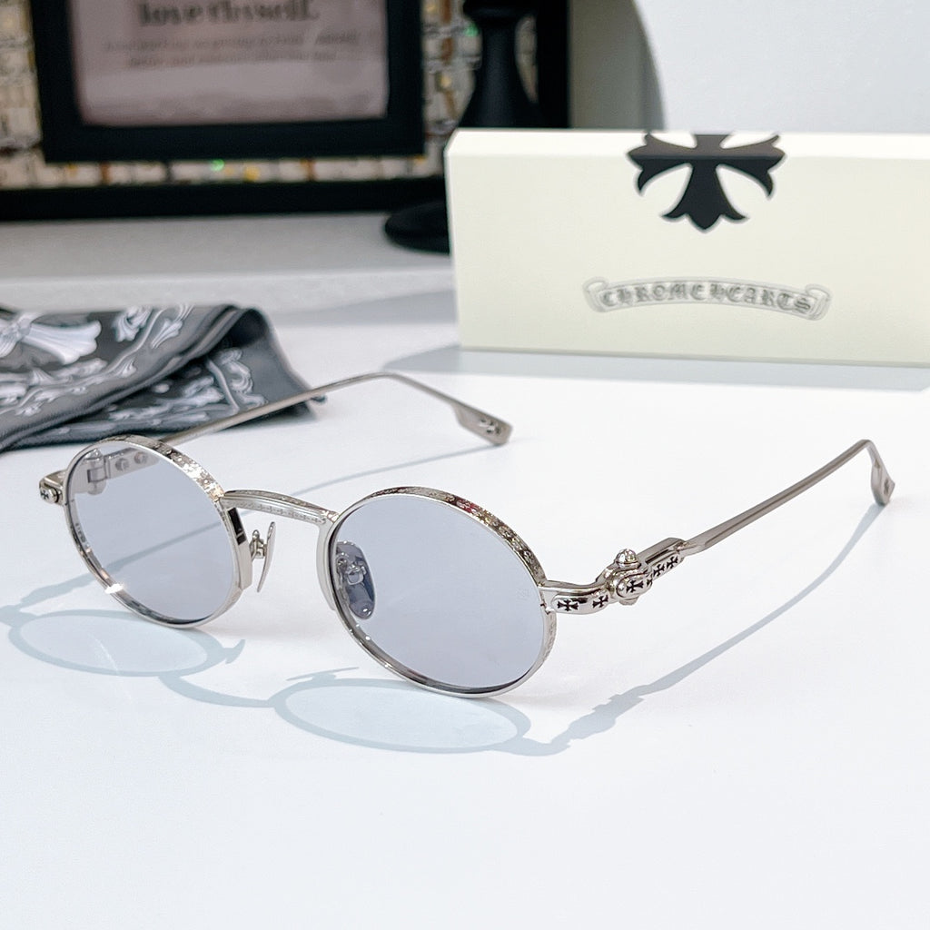 Chrome glasses with silver-tone round frames and clear light-tint lenses, sculpted metal temple detail.
