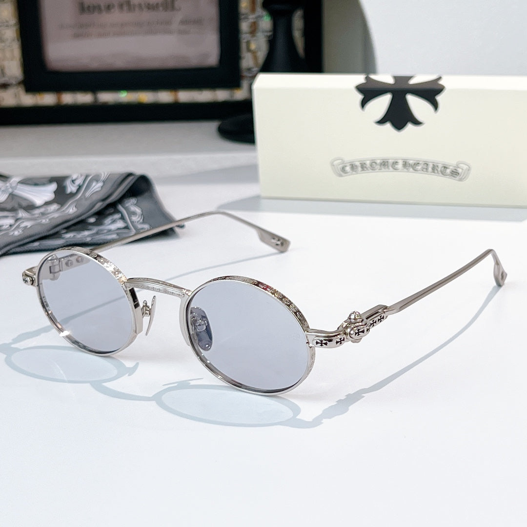 Chrome glasses with silver-tone round frames and clear light-tint lenses, sculpted metal temple detail.