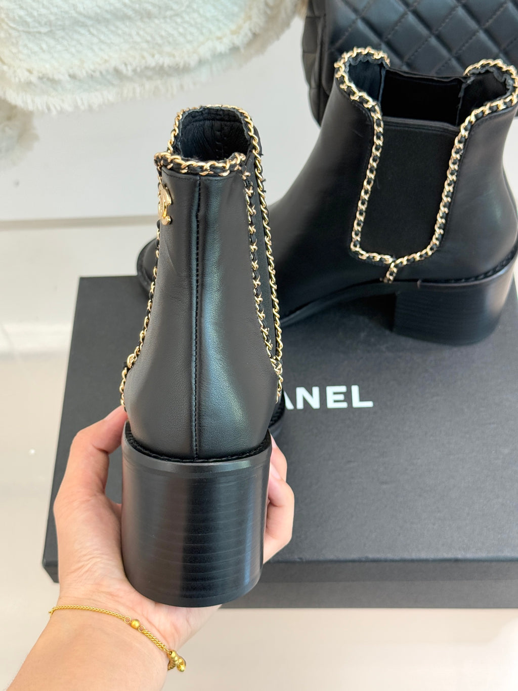 Ladies dark ankle boots from back view with gold chain strap and block heel
