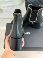 Ladies dark ankle boots from back view with gold chain strap and block heel