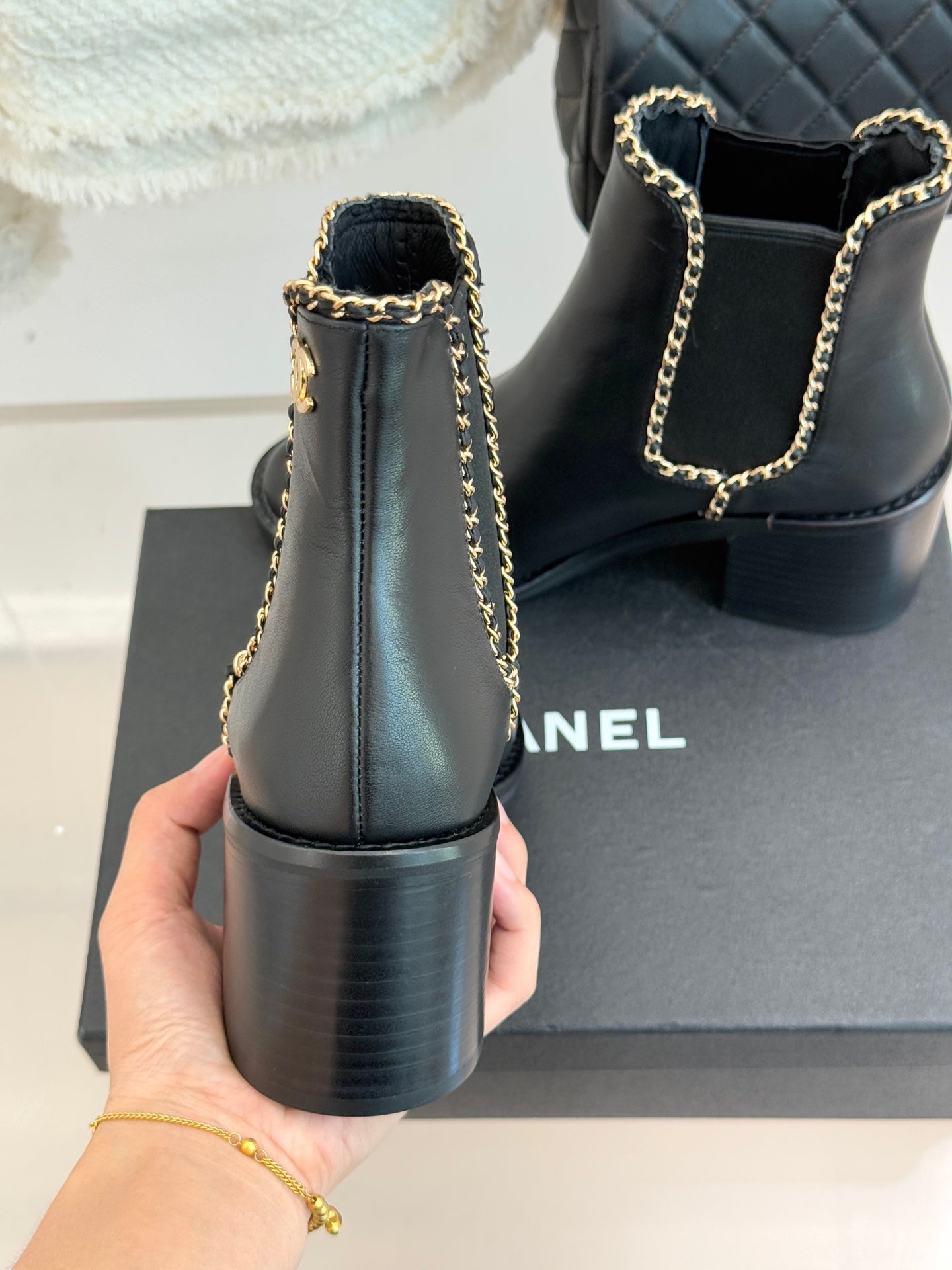 Ladies dark ankle boots from back view with gold chain strap and block heel