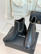 Pair of ladies dark ankle boots with gold chain straps and block heel