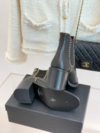 Ladies dark ankle boots on box with gold chain strap and side logo
