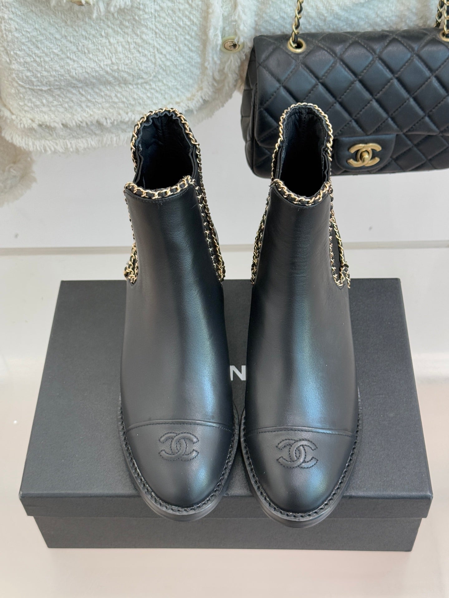 Set of ladies dark ankle boots with gold chain trim and Chanel-style logo