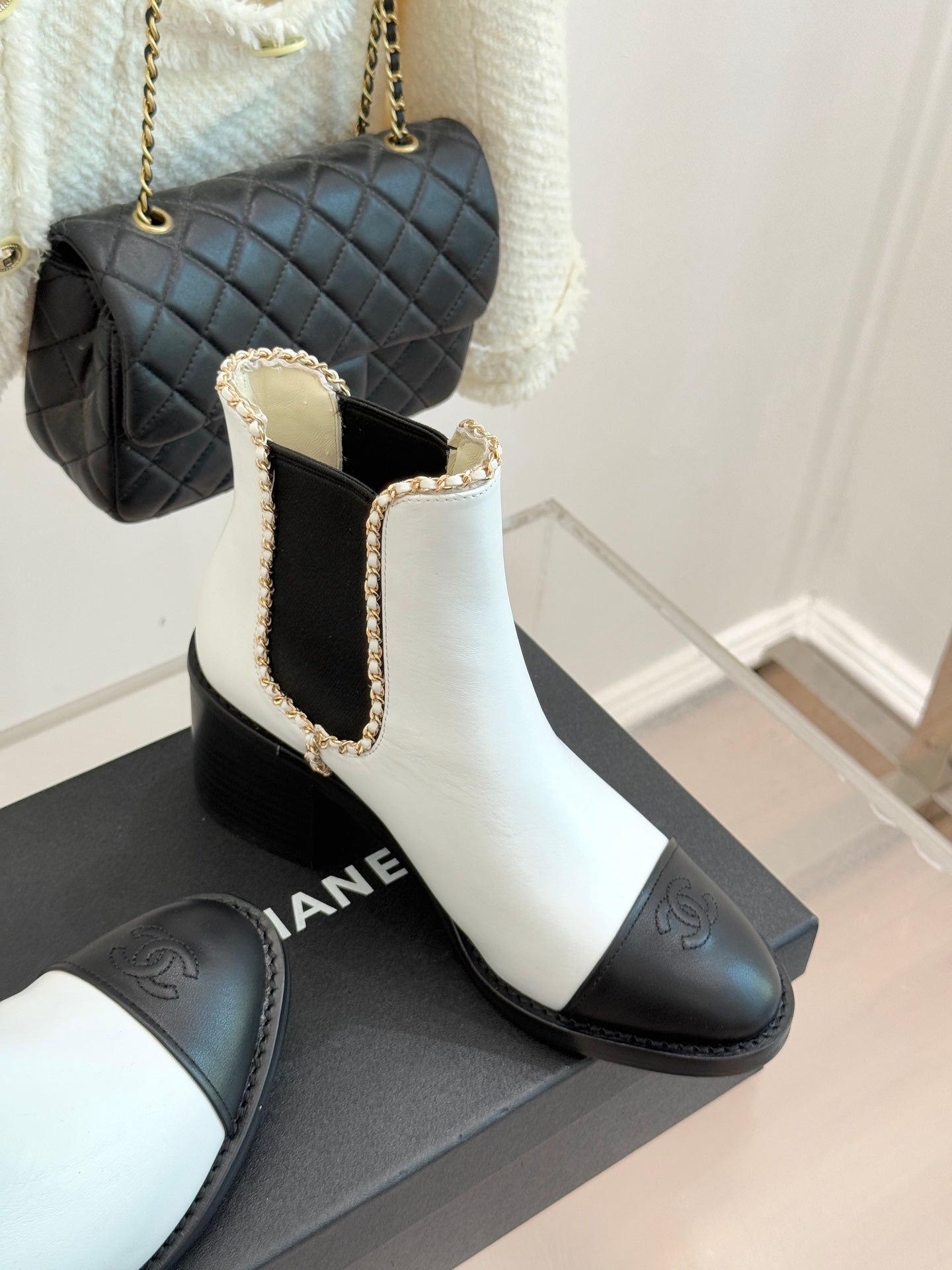 White-and-black Chelsea boots with gold-trimmed elastic panels and block heel.