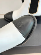 White and black Chelsea boot detail showing black toe cap and embossed logo.