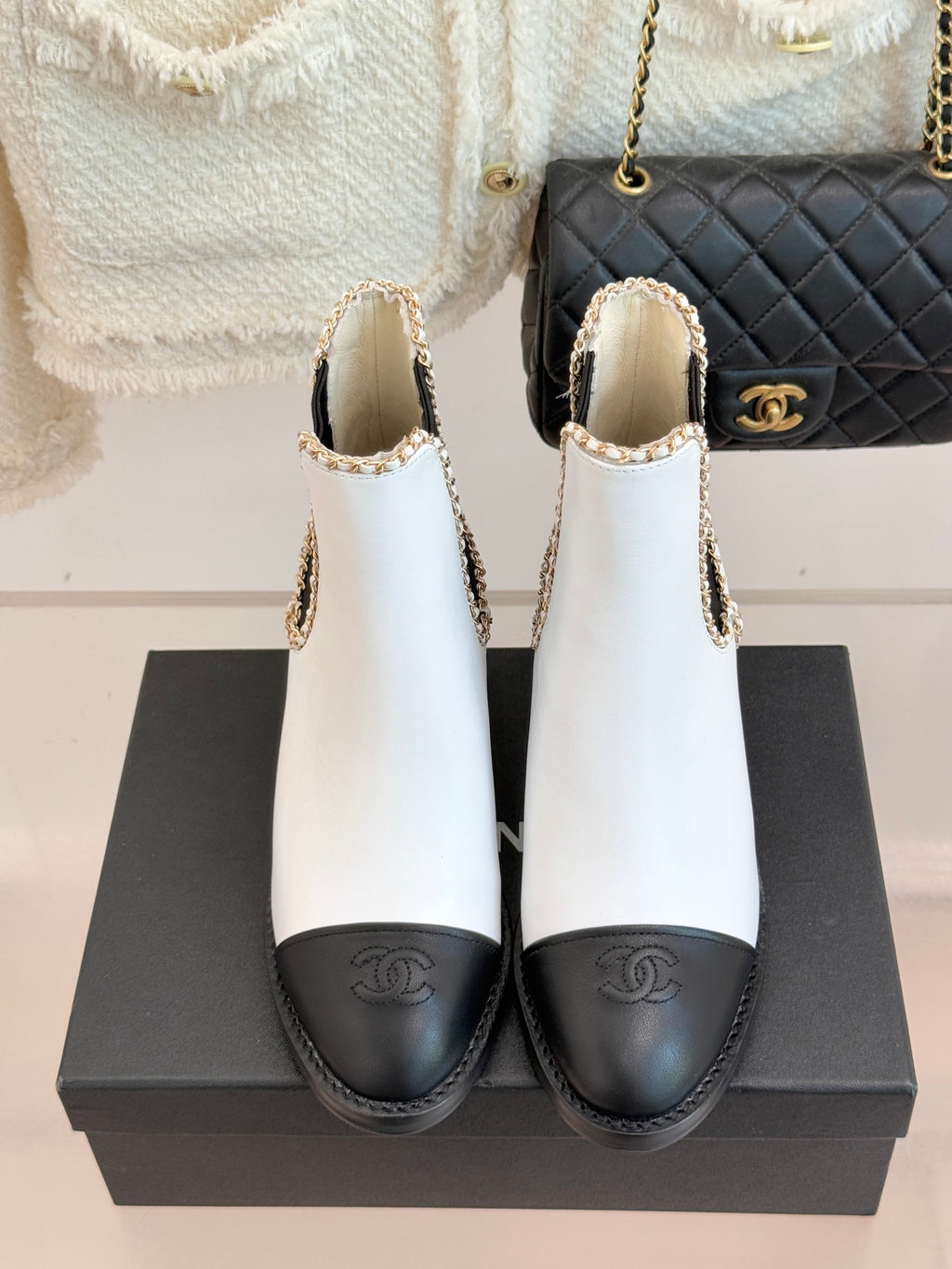 Pair of white Chelsea boots with black elastic sides and gold-trimmed ankle openings.