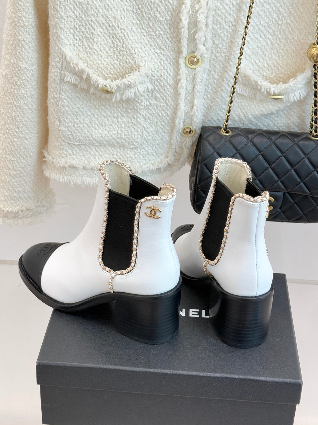 White Chelsea boots with black heel, gold-trimmed collar, and cushioned cuff.