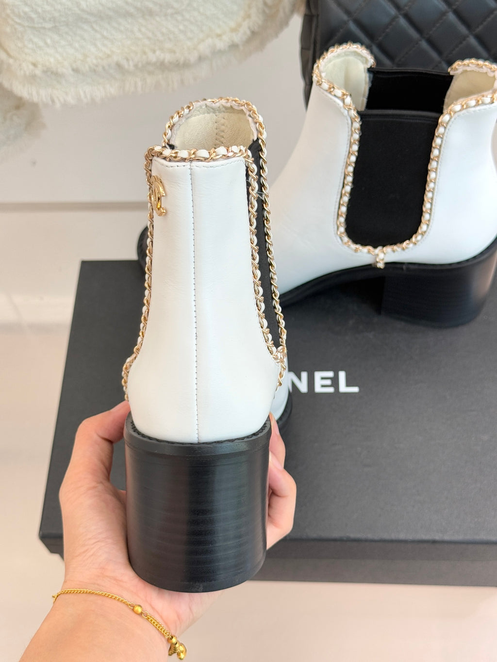 White Chelsea boots with black block heel and gold-trimmed elastic side openings.