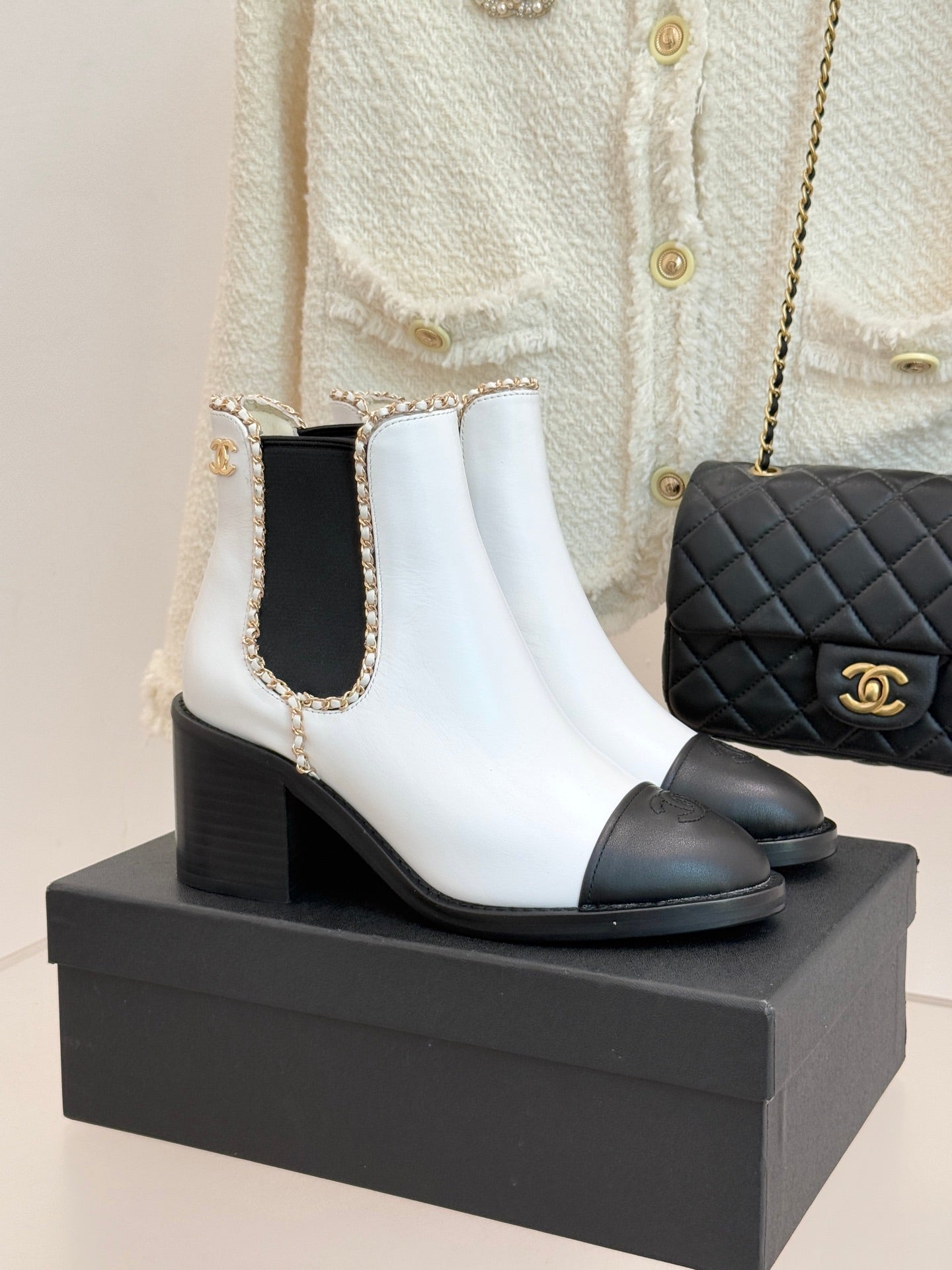 White and black leather Chelsea boots with block heel and gold-trimmed collar.