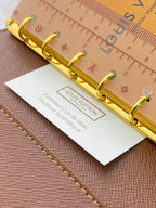 Brown Louis Vuitton small bag close-up of gold ring binder and insert card
