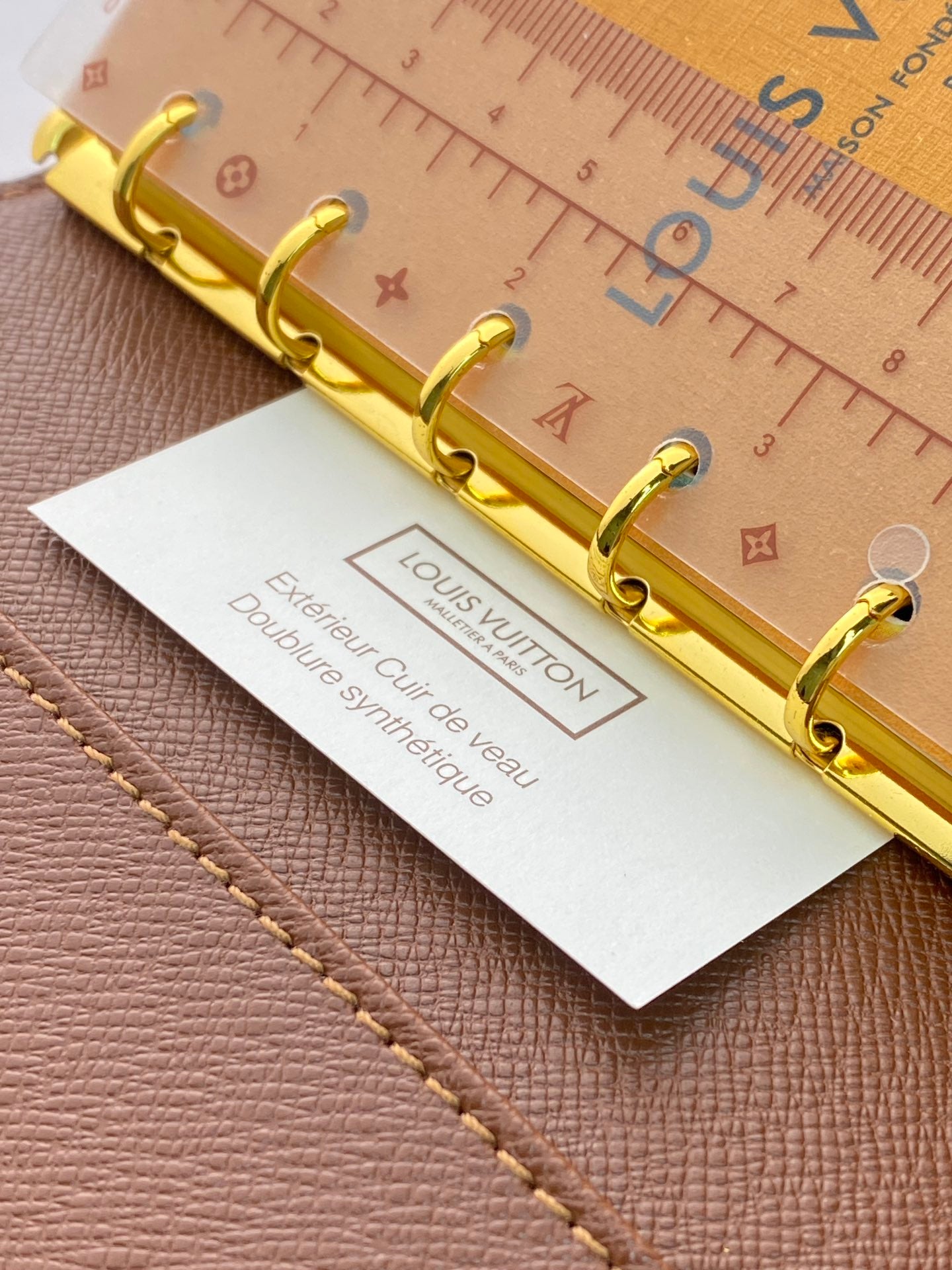 Brown Louis Vuitton small bag close-up of gold ring binder and insert card