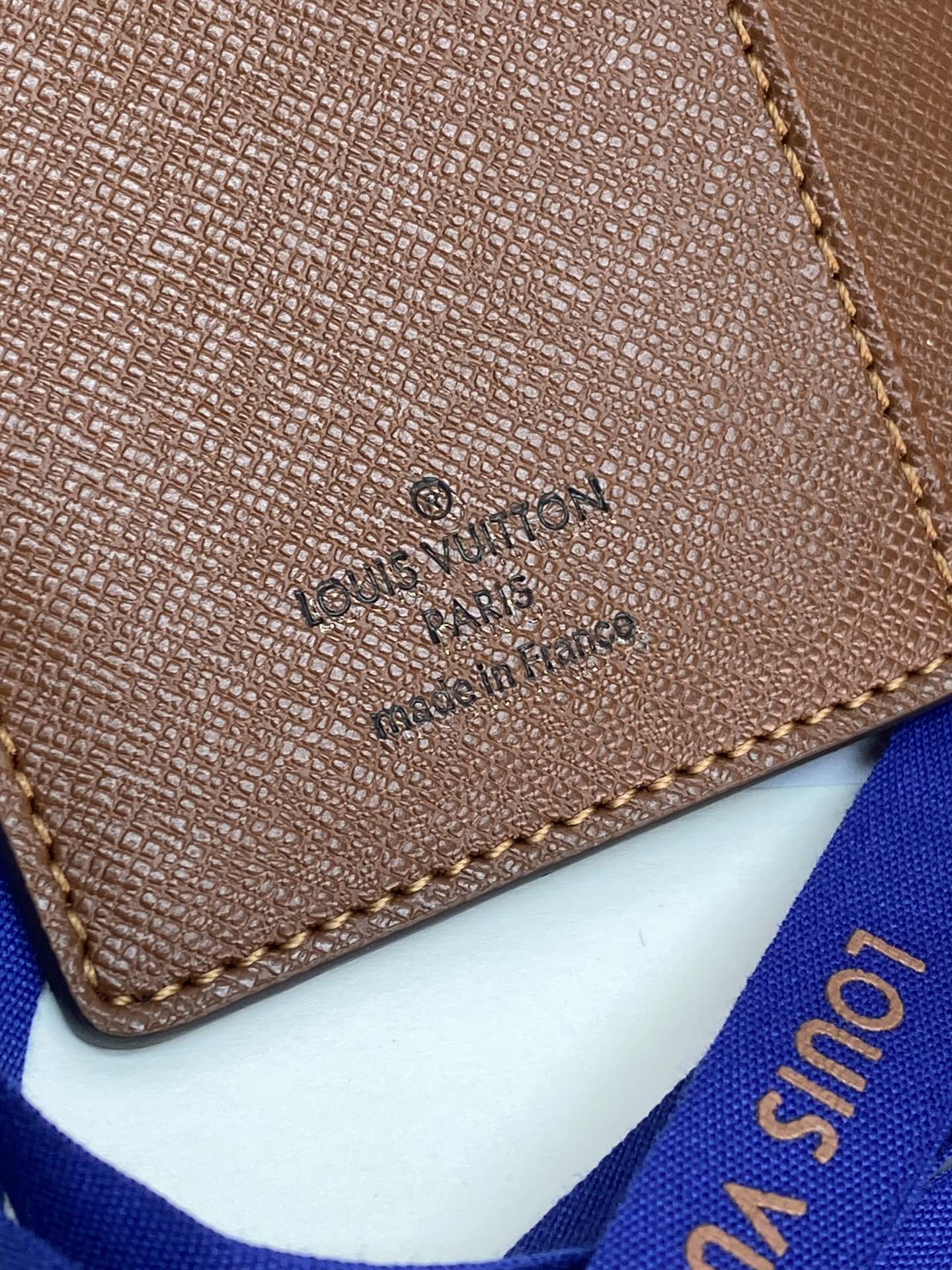 Brown Louis Vuitton small bag close-up of logo stamp and stitched edge