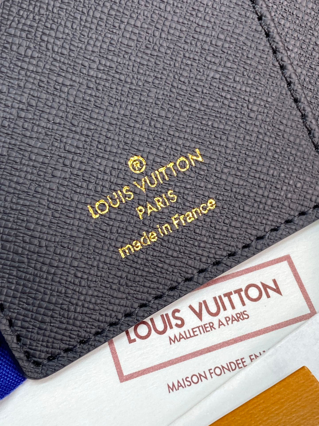 Gray Louis Vuitton small bag with gold embossed logo and Made in France text
